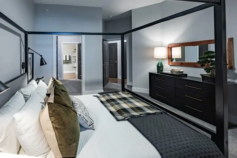 Bedroom with black canopy bed, dresser and walk-through to the bath