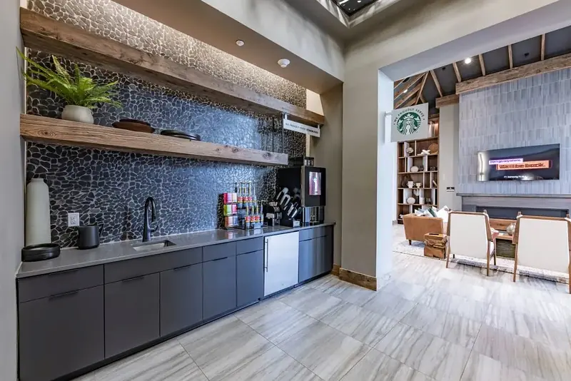 Resident coffee bar with pebble tile backsplash and floating wood shelves