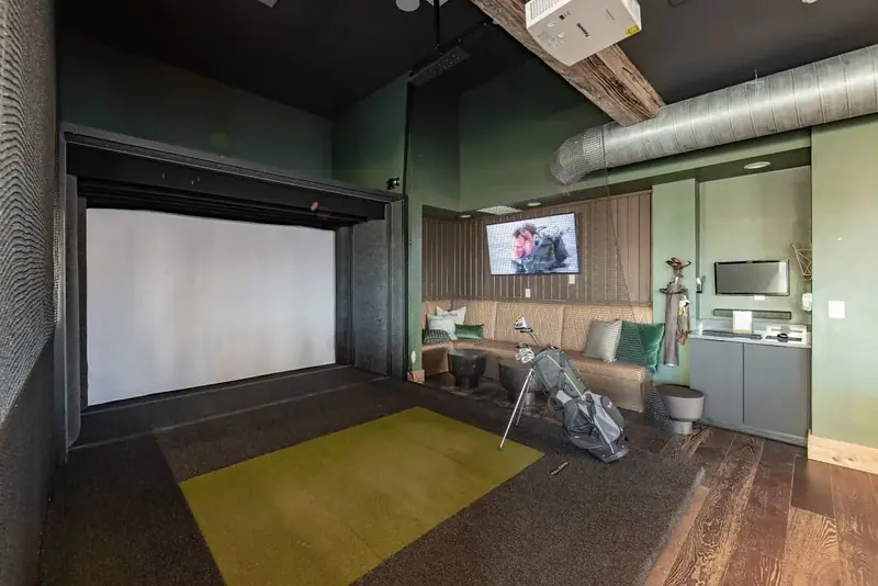Indoor golf simulator room with hitting mat and lounge seating